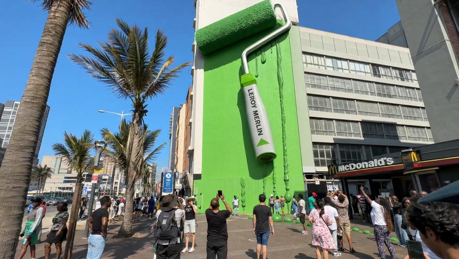 A colossal paint roller painting a downtown Durban building bright green, with the Leroy Merlin name printed on the handle